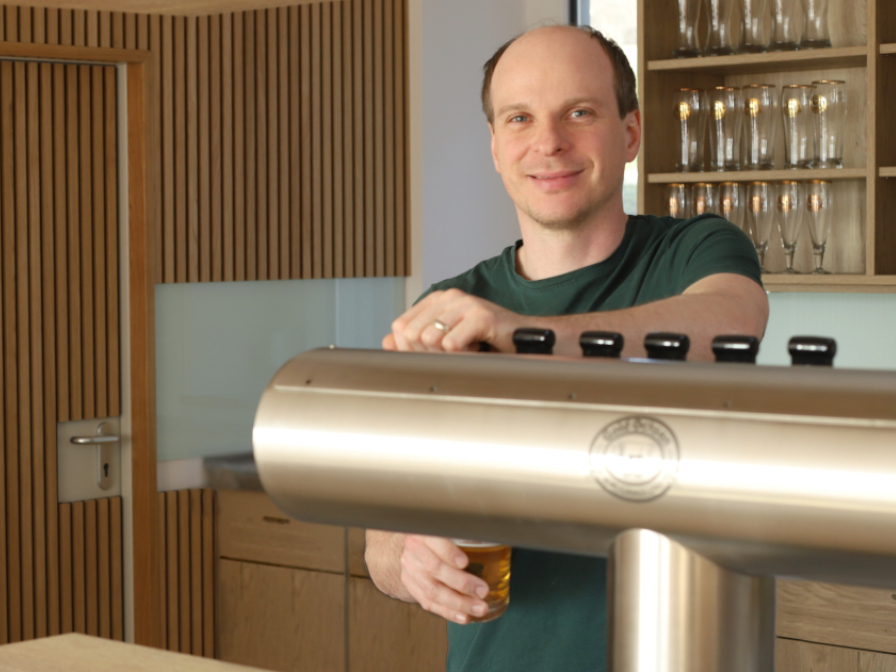 Servicekraft mit vollem Tablett neben einer Theke an der gerade gezapft wird