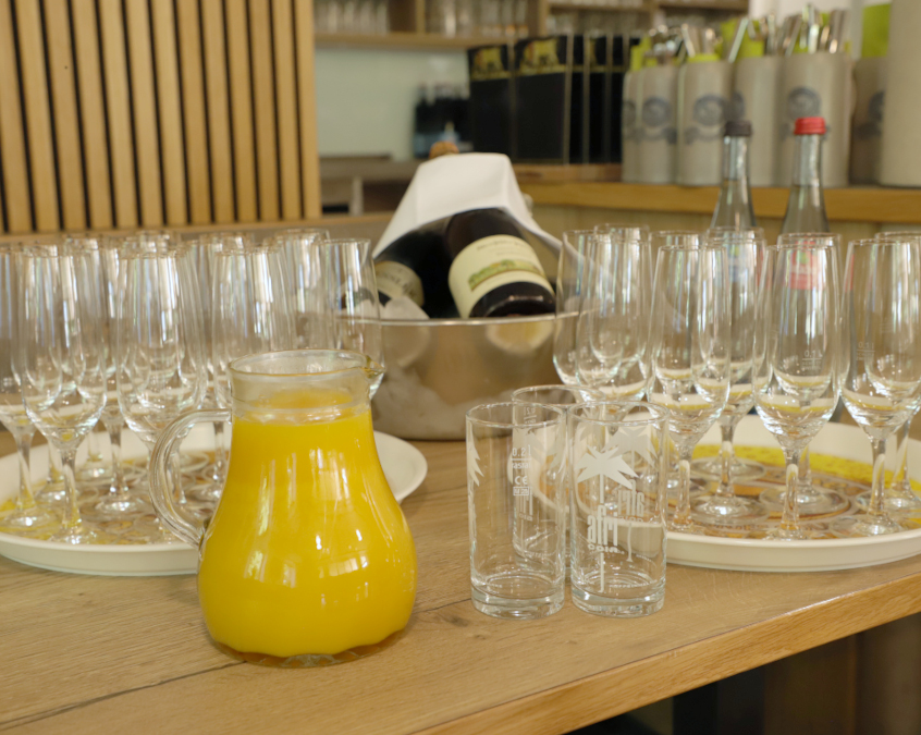 Table with champagne flutes, a carafe of orange juice, and sparkling wine on ice.