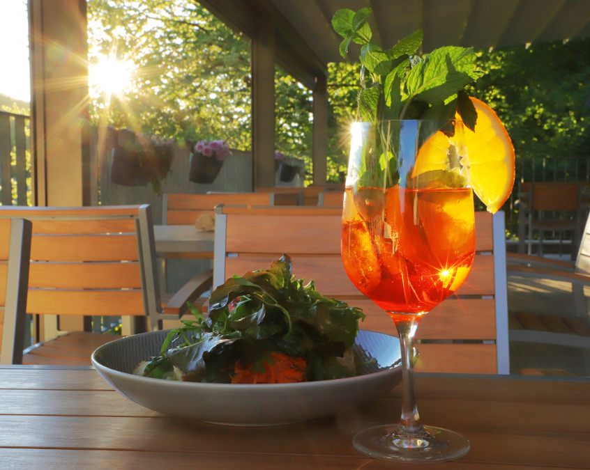 Aperol mit kleinem Salatteller auf der Terrasse beim Sonnenuntergang